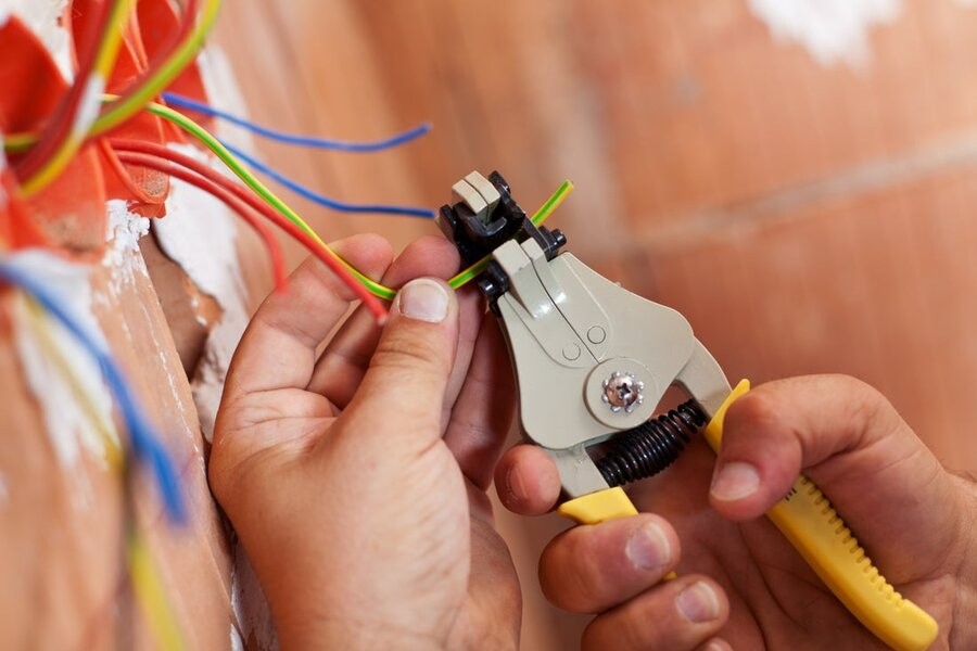 A person’s hands in view working on wiring with a plier tool.