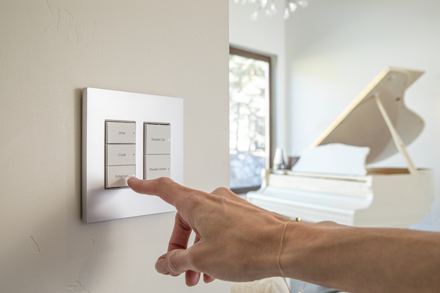 Hand tapping a Control4 Contemporary wall keypad with buttons labeled “Dine,” “Cook” and “Entertain.” 